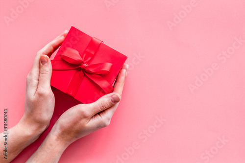 Give a gift on Valentine's Day. Women hand hold beautiful red present box on pink background top-down copy space © 9dreamstudio