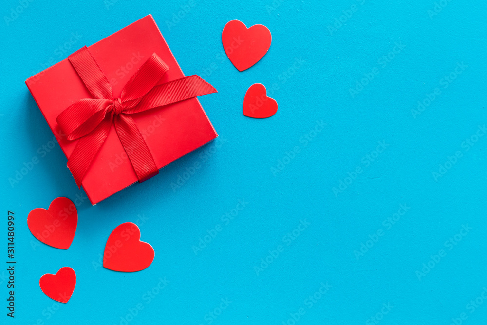 Gift to a sweetheart on Valentine's Day. Red present box near hearts on blue background top-down copy space