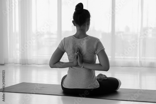Asian woman practicing yoga with namaste behind the back, sitting in seiza exercise vajrasana pose, rear view, Concept of healing body and spirit.