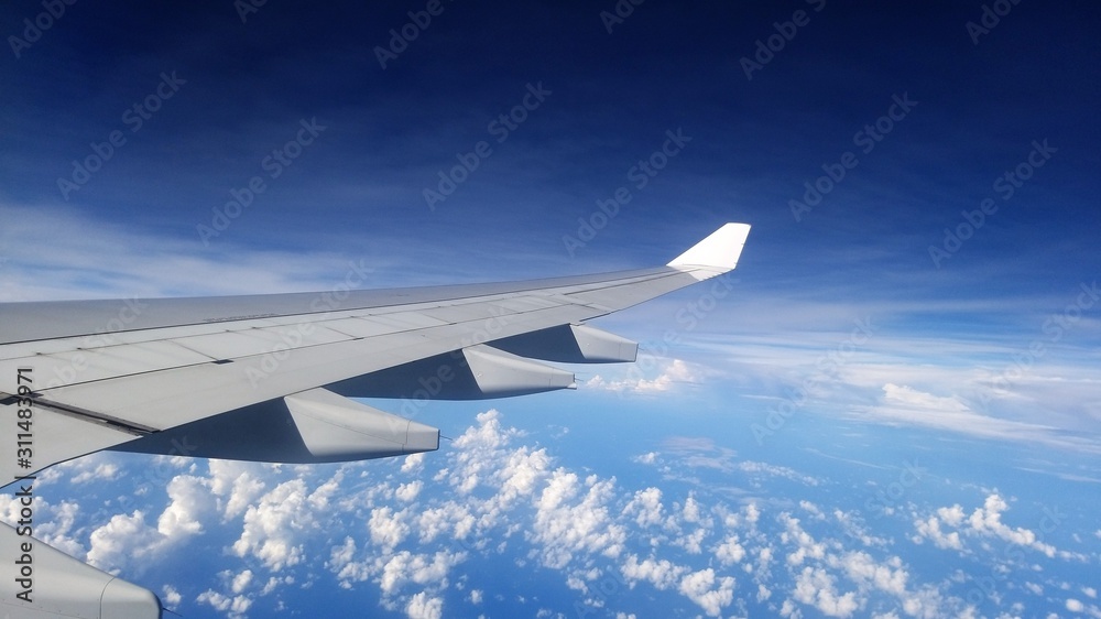 Fototapeta premium Wing of an airplane flying above the clouds