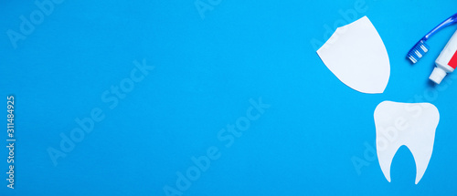 Paper Tooth with a toothbrush and toothpaste on blue background. Space for your text