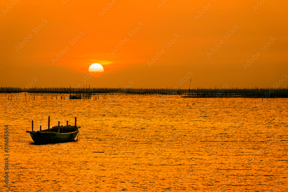 Beautiful summer sunset concept. The sunset at the scene is the oyster farm and the little boat. Boat on the sea beach at sunrise time.
