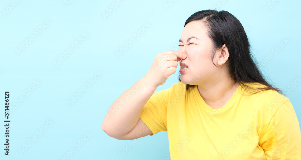 portrait Asia woman feels foul, on blue background in studio With copy space. portrait Asia woman feels foul, on blue background in studio With copy space.