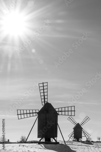 Sun and sunbeams by two old windmills photo