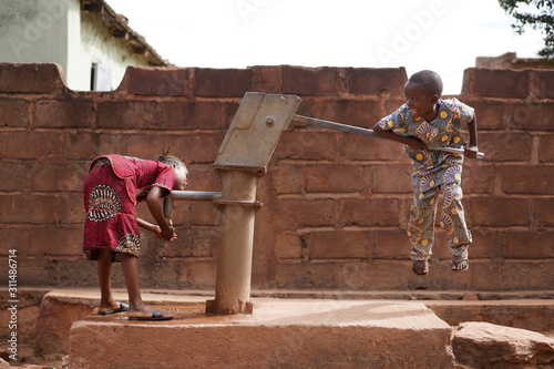 Small African Boy Trying to Pump Water from the Village Well photo