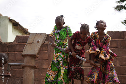 Group of Small West African Girls Pumping Water Together photo