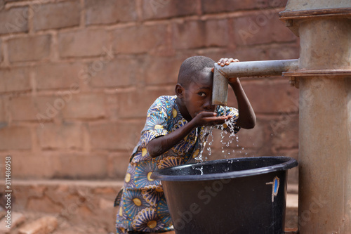 Little African Boy At The Community Borehole Quenching His Thirst  photo