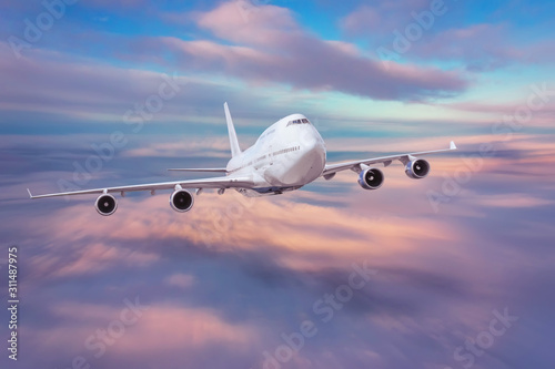 Flying passenger airplane against the background of evening clouds. The concept of tourism, vacation, travel.