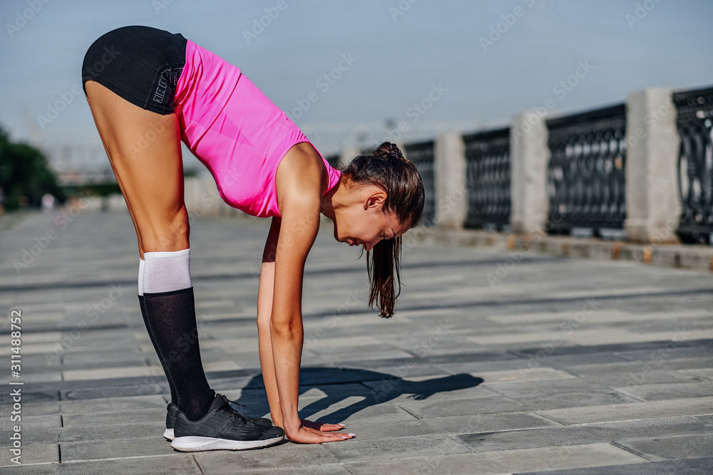 Fitness woman doing stretching exercises on urban city background.