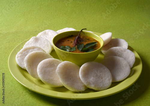 Idli with Sambar in bowl on green background, Indian Dish : south Indian favourite food rava idli or semolina idly or rava idly, served with sambar and green coconut chutney. photo