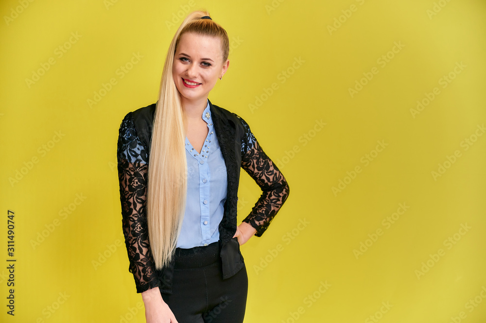 Portrait of a manager woman in a business suit with long beautiful hair and excellent make-up on a yellow background. Concept business blonde girl stands in front of the camera. Portrait of a manager woman in a business suit with long beautiful hair and excellent make-up on a yellow background. Concept business blonde girl stands in front of the camera.