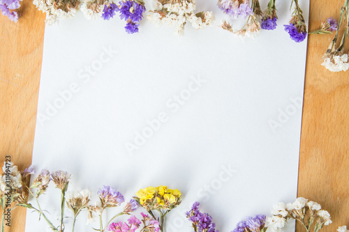 Multicolored dried flowers on wooden background  colorful limonium statice plant with copy space  blank white paper with place for text