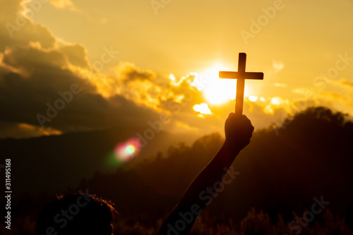 Silhouette of woman praying with cross in nature sunrise background, Crucifix, Symbol of Faith. Christian life crisis prayer to god.