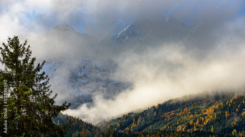 Low cloud layers covering alpine mountain forest in South Tyrol, Italy / Foggy Autumn day