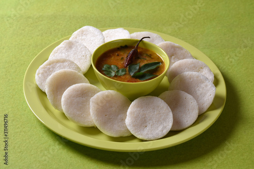 Idli with Sambar in bowl on green background, Indian Dish : south Indian favourite food rava idli or semolina idly or rava idly, served with sambar and green coconut chutney. photo