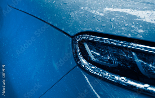 Beautiful rain drops on the car of trendy blue. Wet car body of trendy blue color. 2020 color trend.