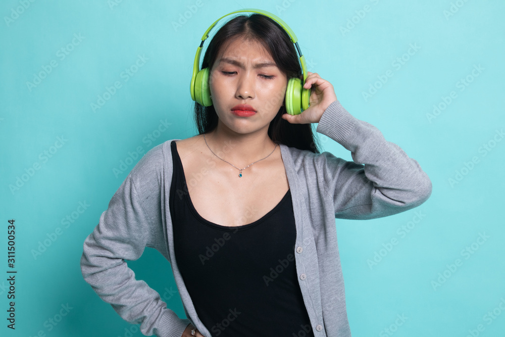 Too loud. portrait of young asian woman holding headphones and making unhappy face. Too loud. portrait of young asian woman holding headphones and making unhappy face.