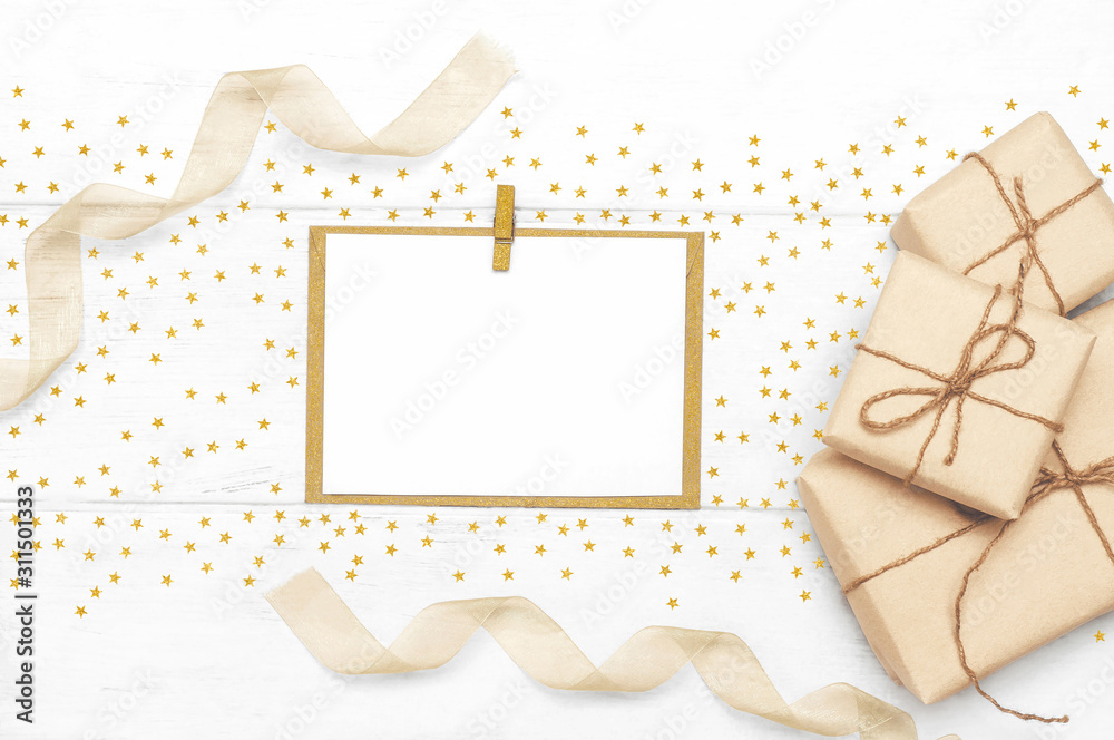 Gift boxes wrapped in eco paper and rope with golden stars, ribbons blank postcard on a white wooden background boards. Gifts for holiday concept. Top view. Flat lay