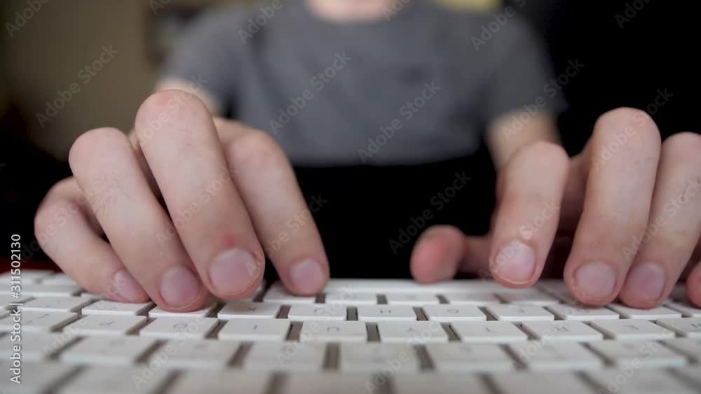 The masculine hands are typing on a white keyboard zoomed in fingers The masculine hands are typing on a white keyboard zoomed in fingers