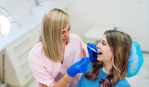 Attractive young woman in stomatology clinic with cheerful female dentist. Healthy teeth concept.