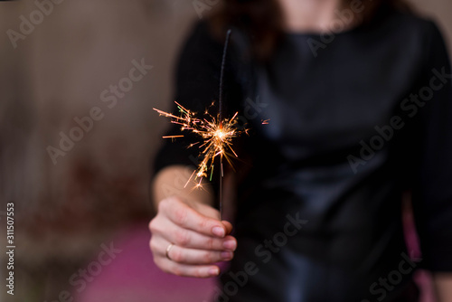 Girl holds sparkler in her hands, soft focus