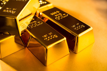 Shiny fine gold bullions on a gold background.