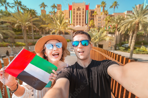 Selfie of a loving couple of man and woman holding UAE national flag. Travel and immigration in Dubai and United Arab Emirates concept photo