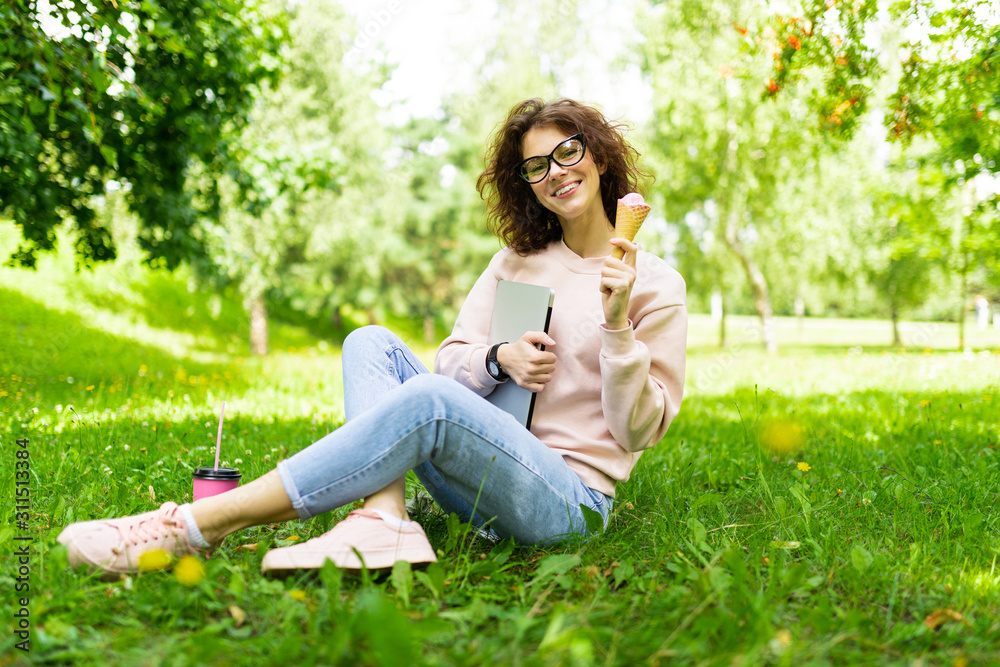 freelance concept. girl sitting on grass with laptop and ice cream freelance concept. girl sitting on grass with laptop and ice cream