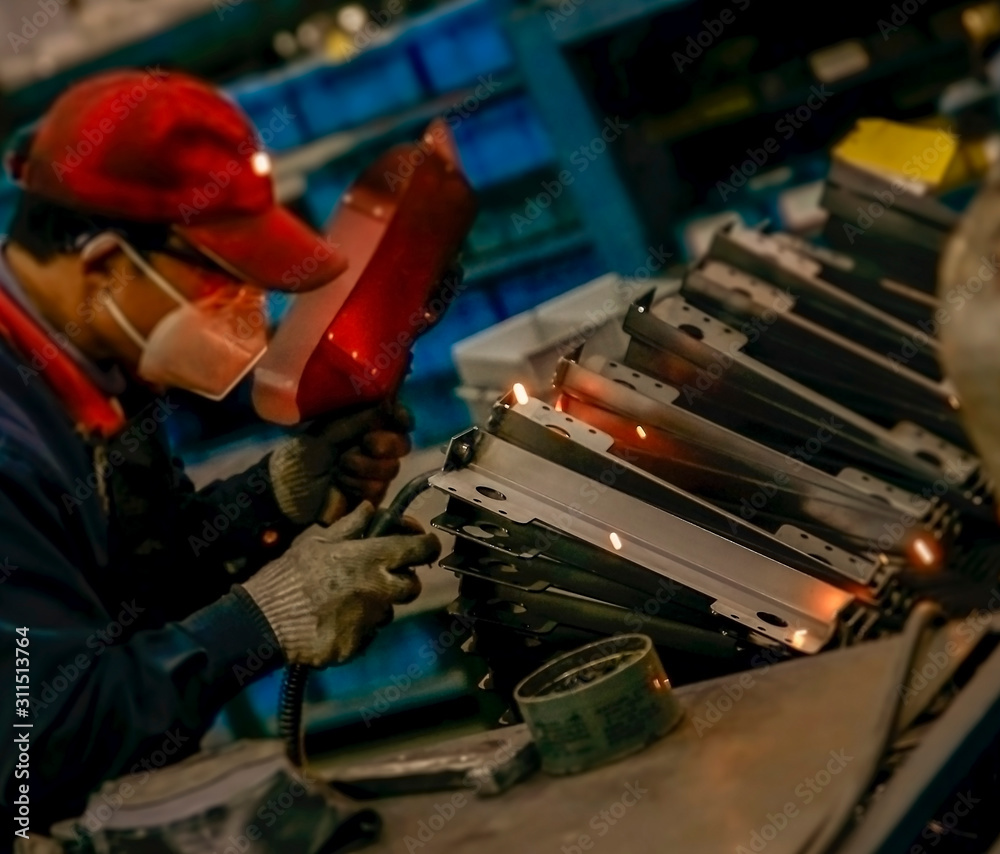 Worker doing spot welding in dim workshop Worker doing spot welding in dim workshop