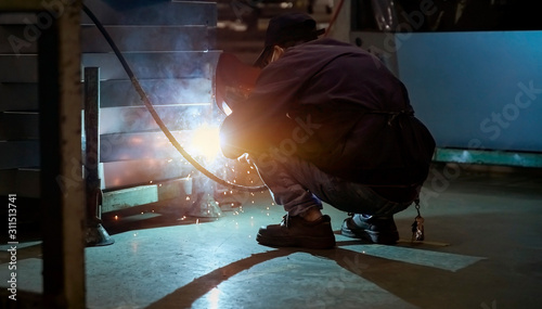 Worker doing spot welding in dim workshop