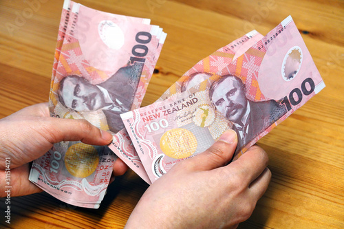 Woman hands counting New Zealand dollars banknotes. photo