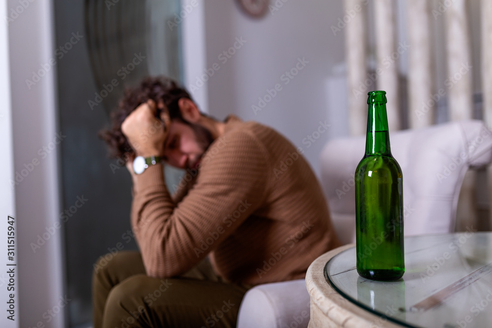 Depressed sad young addicted man feeling bad drinking beer alone at home, stressed frustrated lonely drinker alcoholic suffer from alcohol addiction having problem, alcoholism concept Depressed sad young addicted man feeling bad drinking beer alone at home, stressed frustrated lonely drinker alcoholic suffer from alcohol addiction having problem, alcoholism concept