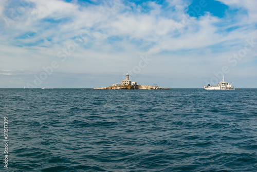 A seascape. A small island with a lighthouse and yachts in the Adriatic Sea near Rovinj. Croatia. Istria