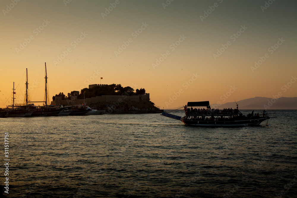 Kusadasi, Turkey - September 17, 2019: Castle on Pigeon Island in Kusadasi, Turkey. Historic Byzantine fortress on the sea.  Boat trip during sunset.