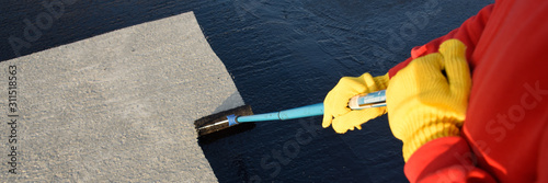Fotografía Worker applies bitumen mastic on the foundation