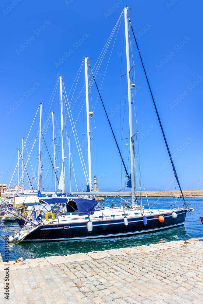 Yachts with lowered sails on the pier in the bay of the Mediterranean city