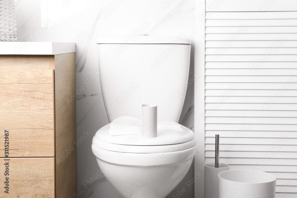 Empty paper roll on toilet bowl in bathroom Empty paper roll on toilet bowl in bathroom