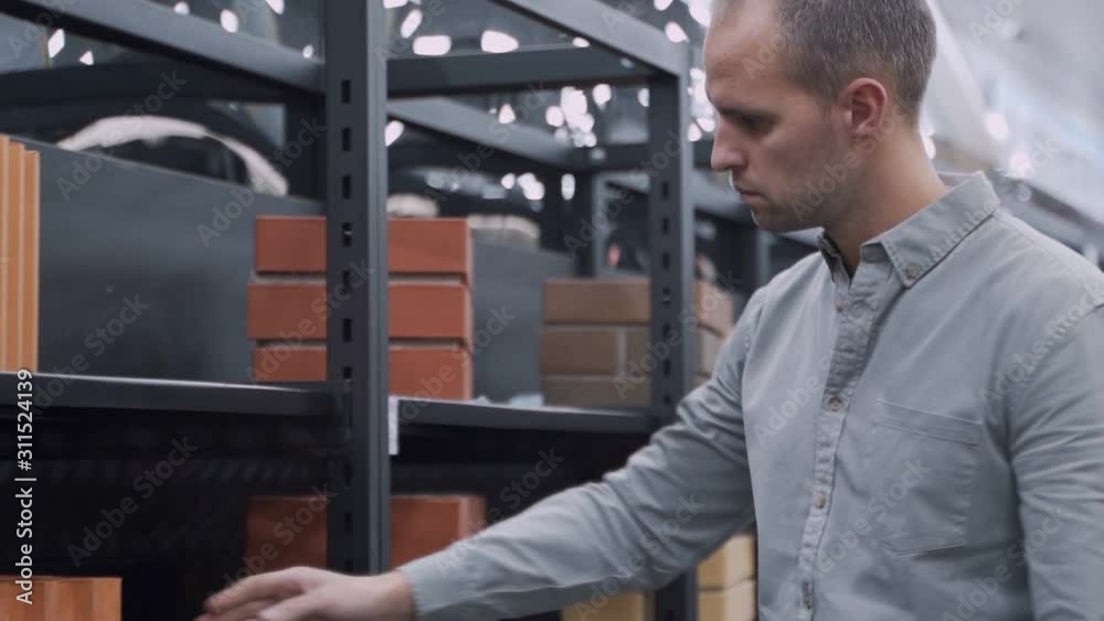 Male Builder Choosing Bricks In Hardware Store Male Builder Choosing Bricks In Hardware Store