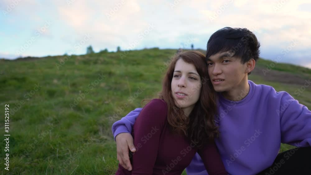 Gimbal Rotating Shot of Young Multi Ethnic Couple Sitting Together in Grass in Outdoor Scenery Gimbal Rotating Shot of Young Multi Ethnic Couple Sitting Together in Grass in Outdoor Scenery