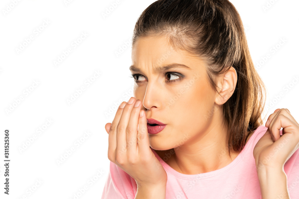 Young woman checking her breath with her palm on white background Young woman checking her breath with her palm on white background