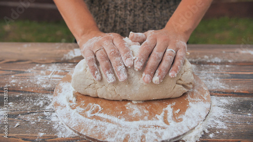 A young woman kneads the dough with her hands. Homemade bread baking.