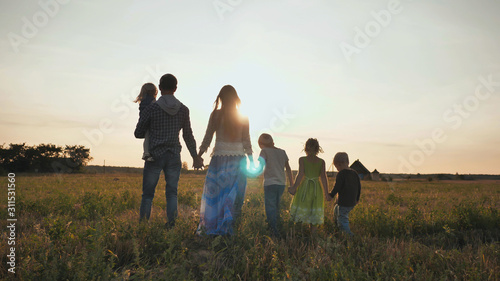 A large family walks along the field at sunset.