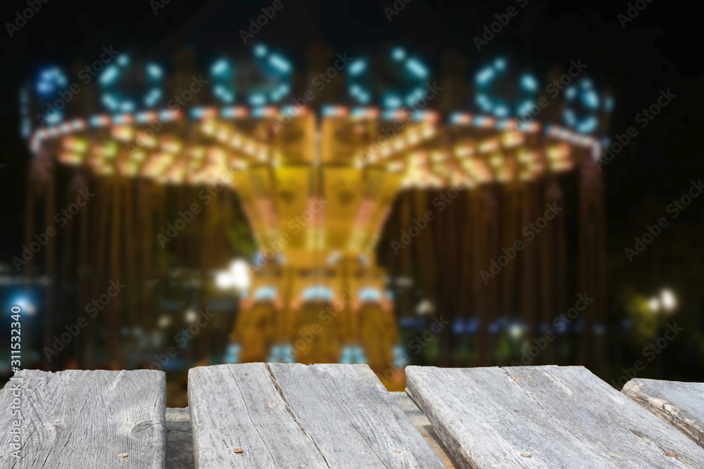 An empty wooden table on a blurred carousel background in night An empty wooden table on a blurred carousel background in night