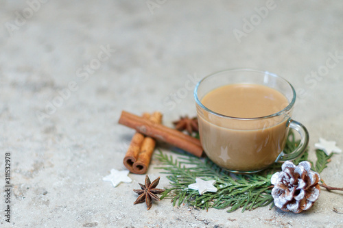 Cup of coffee, pine cone, cinnamon sticks and anise stars on a green branch of cypress. New Year's breakfast design. Selective focus, copy space