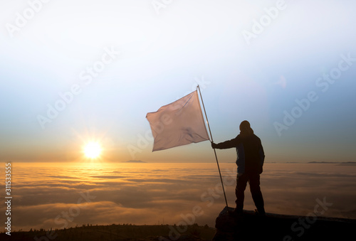 successful man silhouette holding white flag at summit
