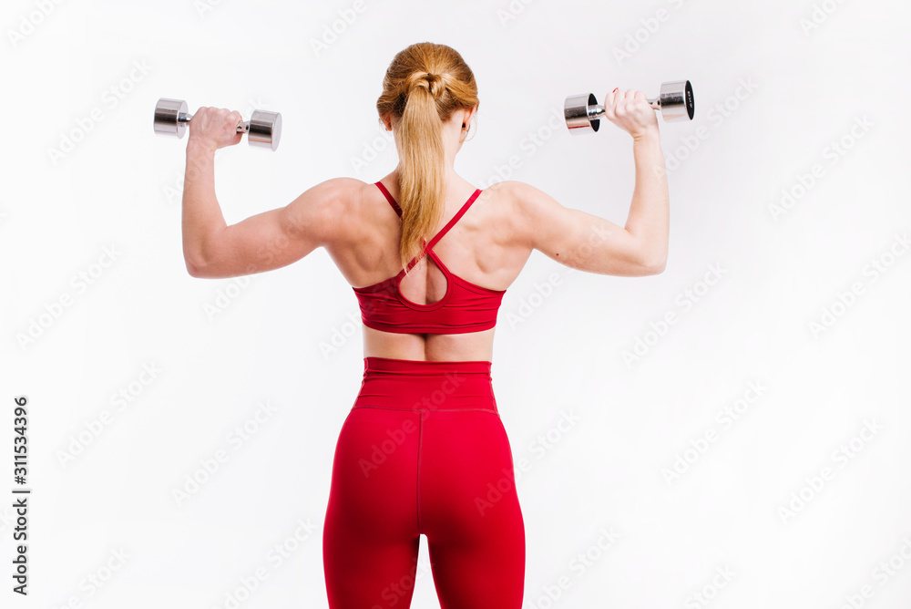 Young strong and sporty woman in red cloth doing exercises with dumbbells on white background Young strong and sporty woman in red cloth doing exercises with dumbbells on white background