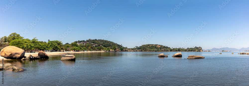 Fototapeta premium Panorama of Jose Bonifacio Beach, with rocks in the corner, cloudless blue sky, Paqueta, Rio de Janeiro, Brazil