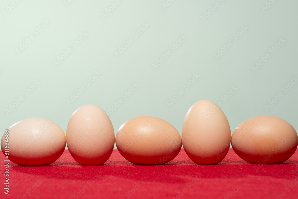 Whole eggs with set in a row on red background. Whole eggs with set in a row on red background.