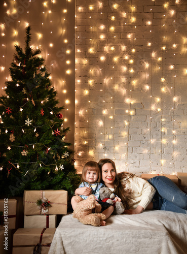 Young mother and her daughters near the Christmas tree. © FAB.1