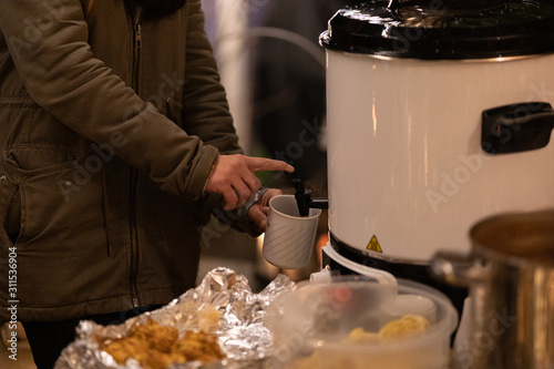 Woman pours mulled wine from a heat container